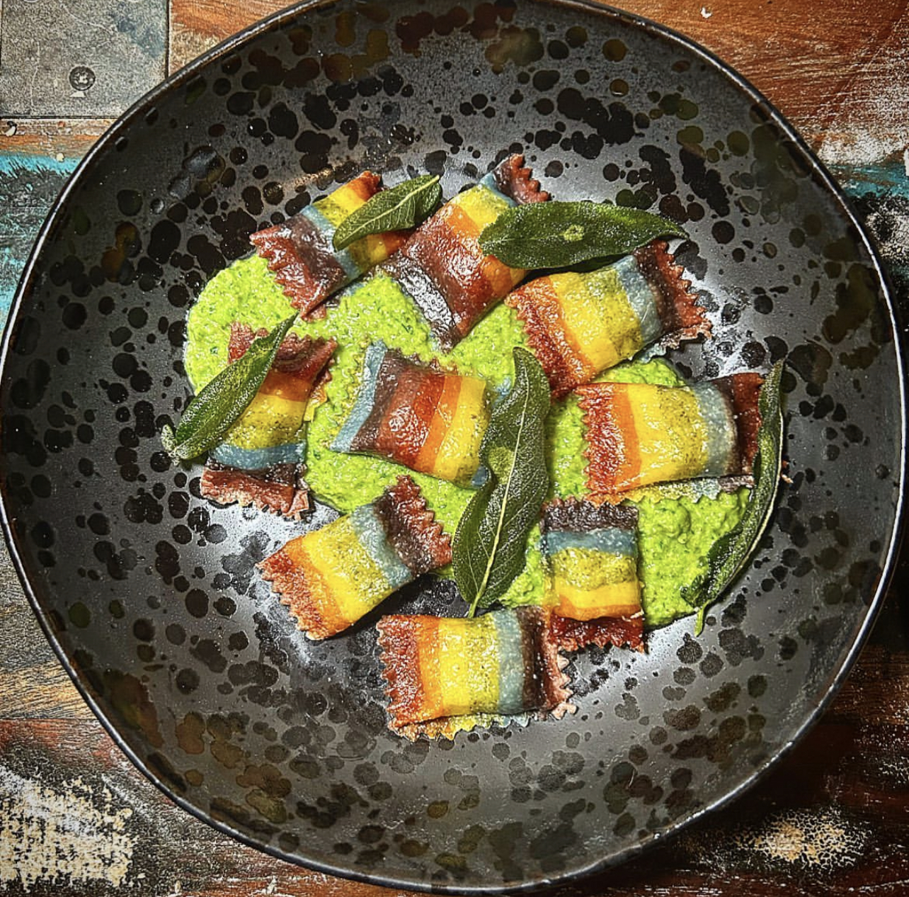 Rainbow ravioli over bright green herb sauce